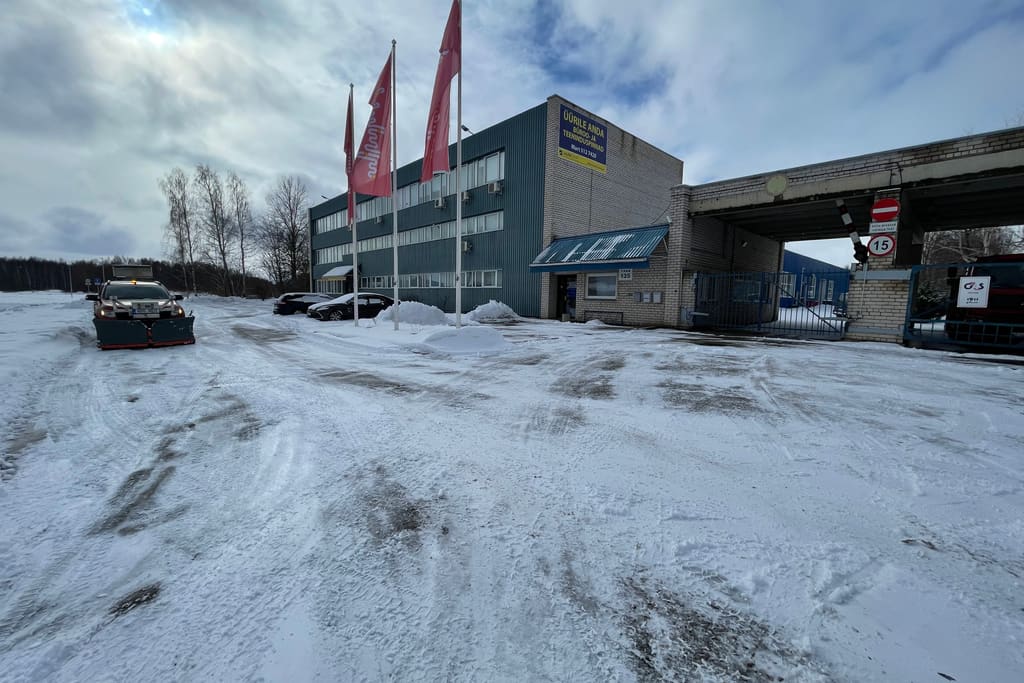Lumine ärihoone parkla, kaugemal töötab sahaga masin, hoone ees lehvivad lipud